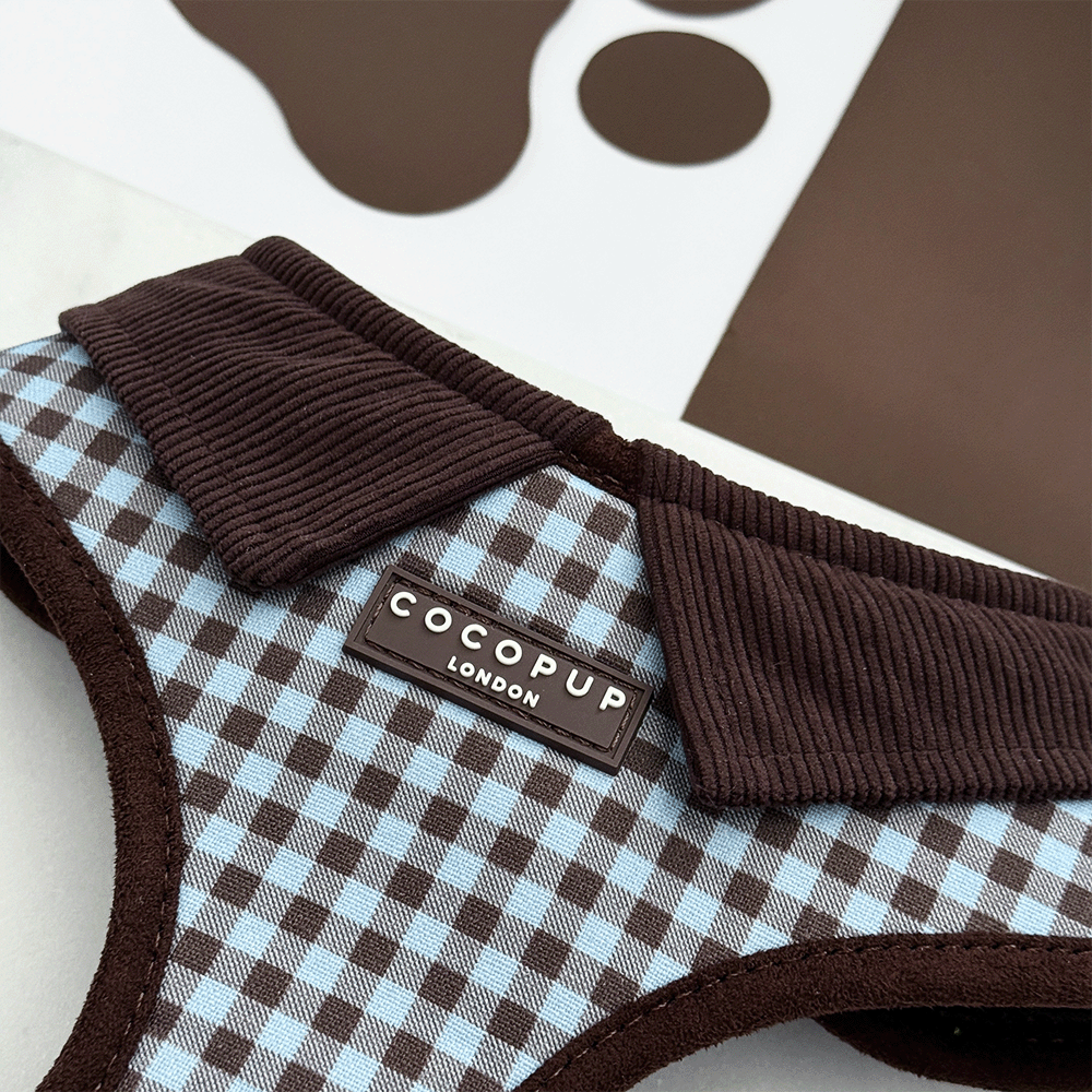 A brown and blue check print dog harness. With brown hardware and brown corduroy collar detail.