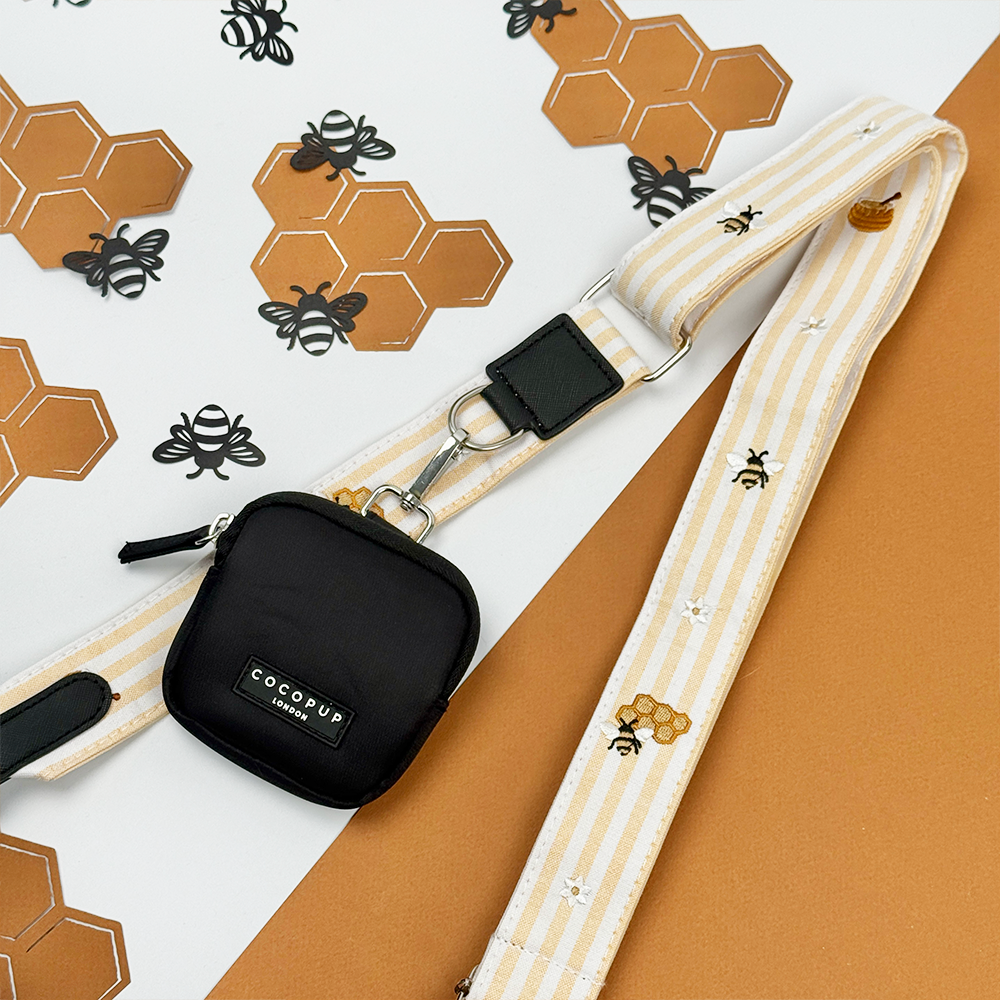Pale yellow and white striped Bag Strap with bee and honeycomb embroidered decals. Attached is a Cocopup Treat Pouch in black.
