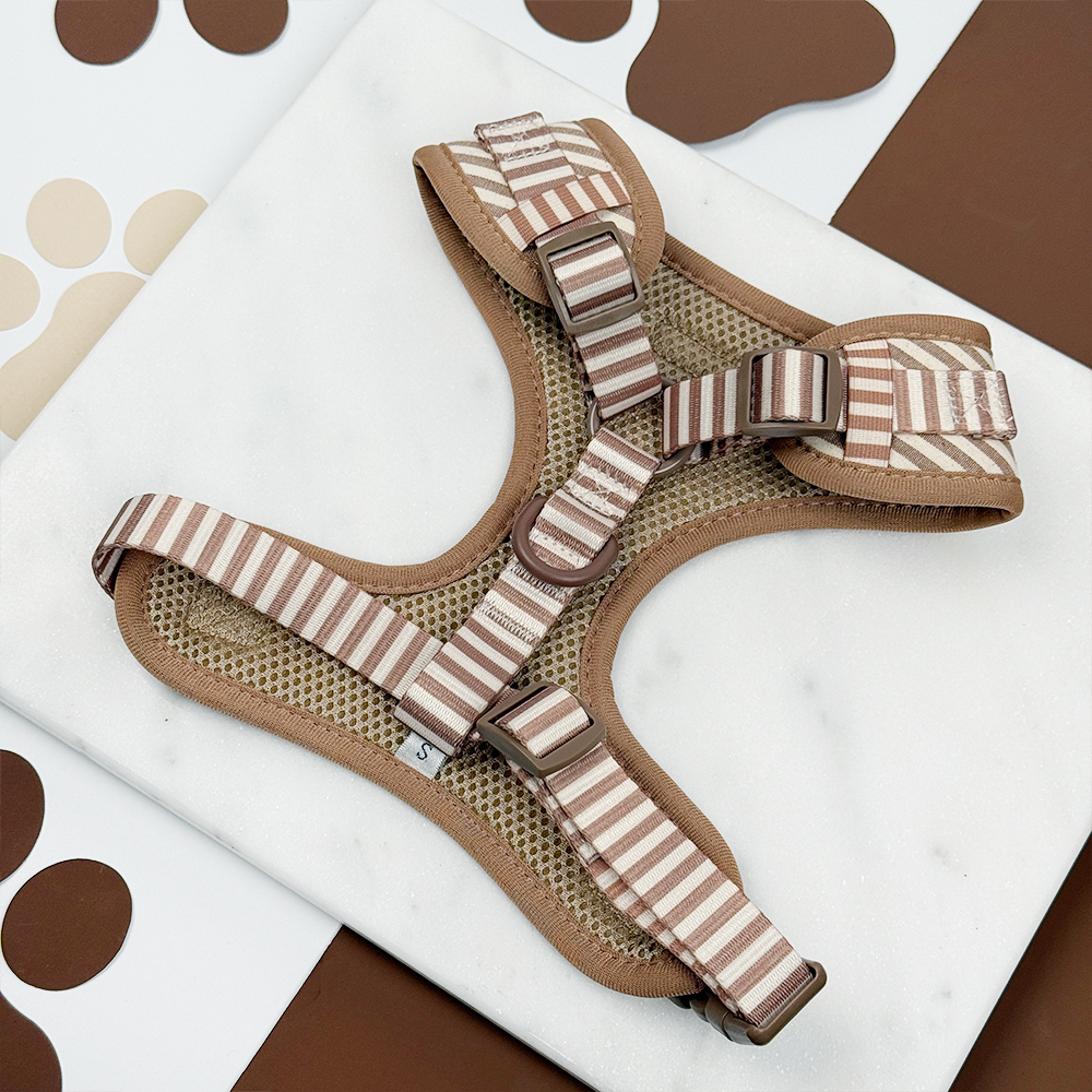 Back of a beige and brown dog harness on a white surface.