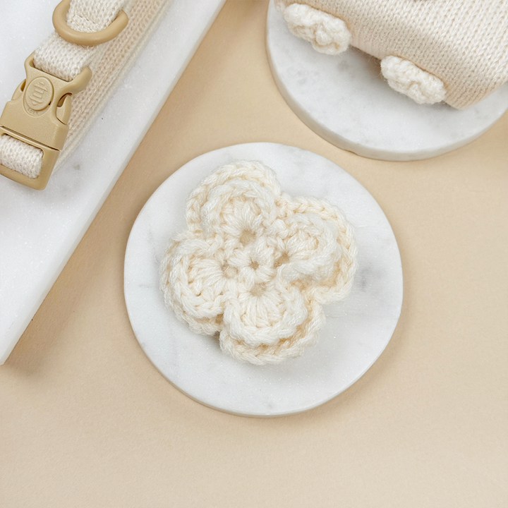 Cream crocheted Dog Collar Flower with beige background.