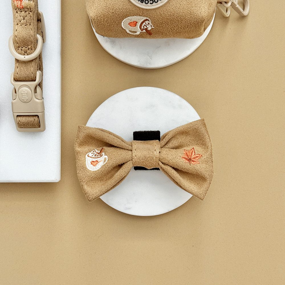 Brown dog bow tie with autumnal-themed embroidery of pumpkins, leaves, a coffee cup, and mushrooms.