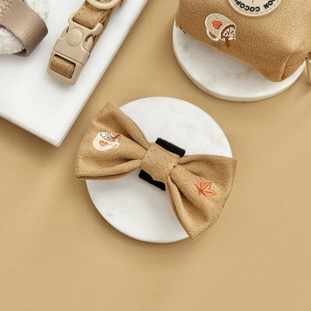 Brown dog bow tie, with autumnal-themed embroidery of pumpkins, leaves, a coffee cup, and mushrooms.