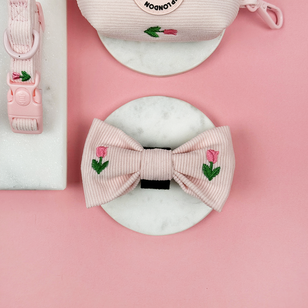 Pink dog bow with floral tulip embroidery on a pink background.