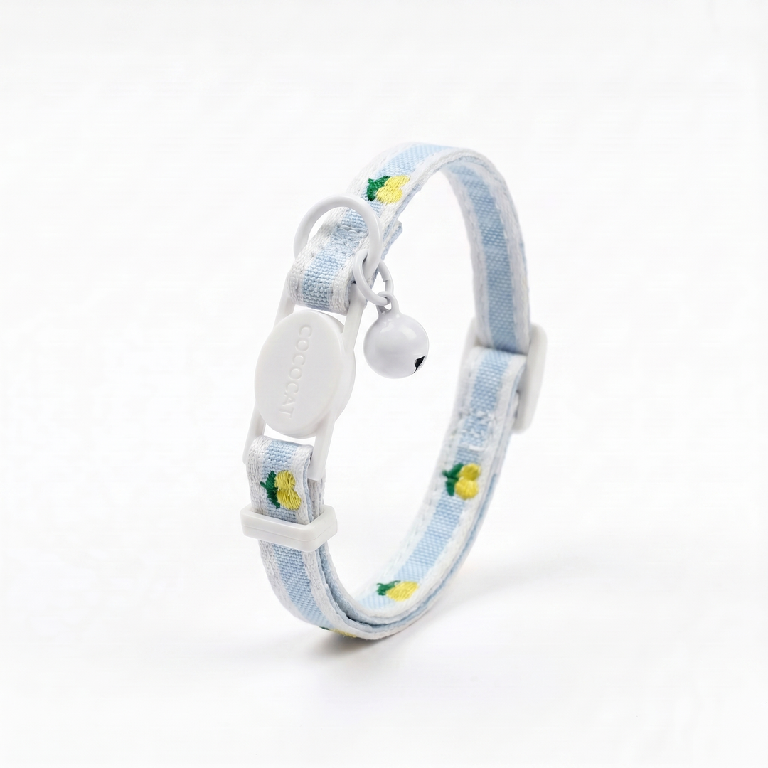 Yellow cat collar with lemon pattern, adjustable breakaway buckle, and white bell on a white background.