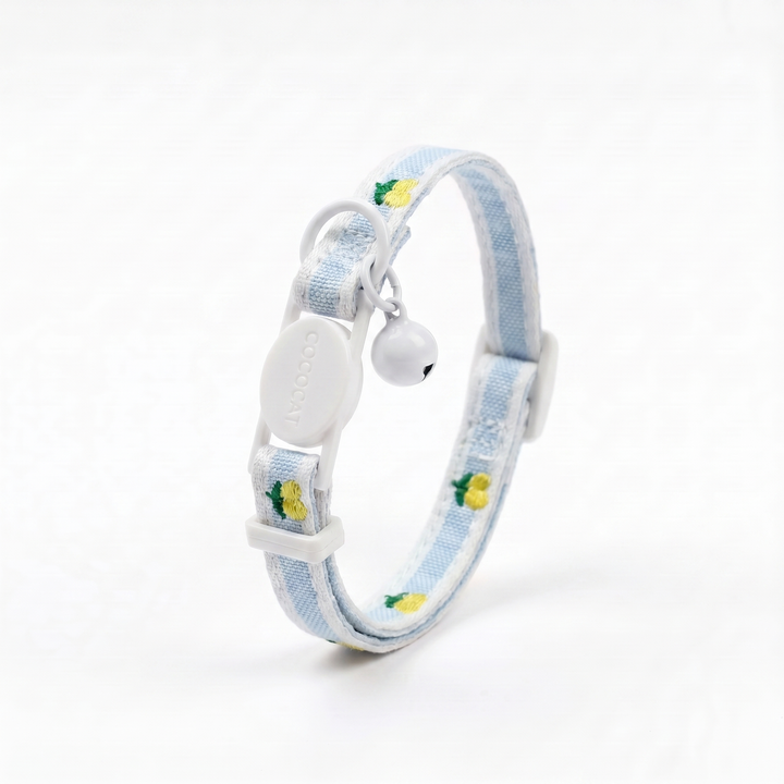 Yellow cat collar with lemon pattern, adjustable breakaway buckle, and white bell on a white background.