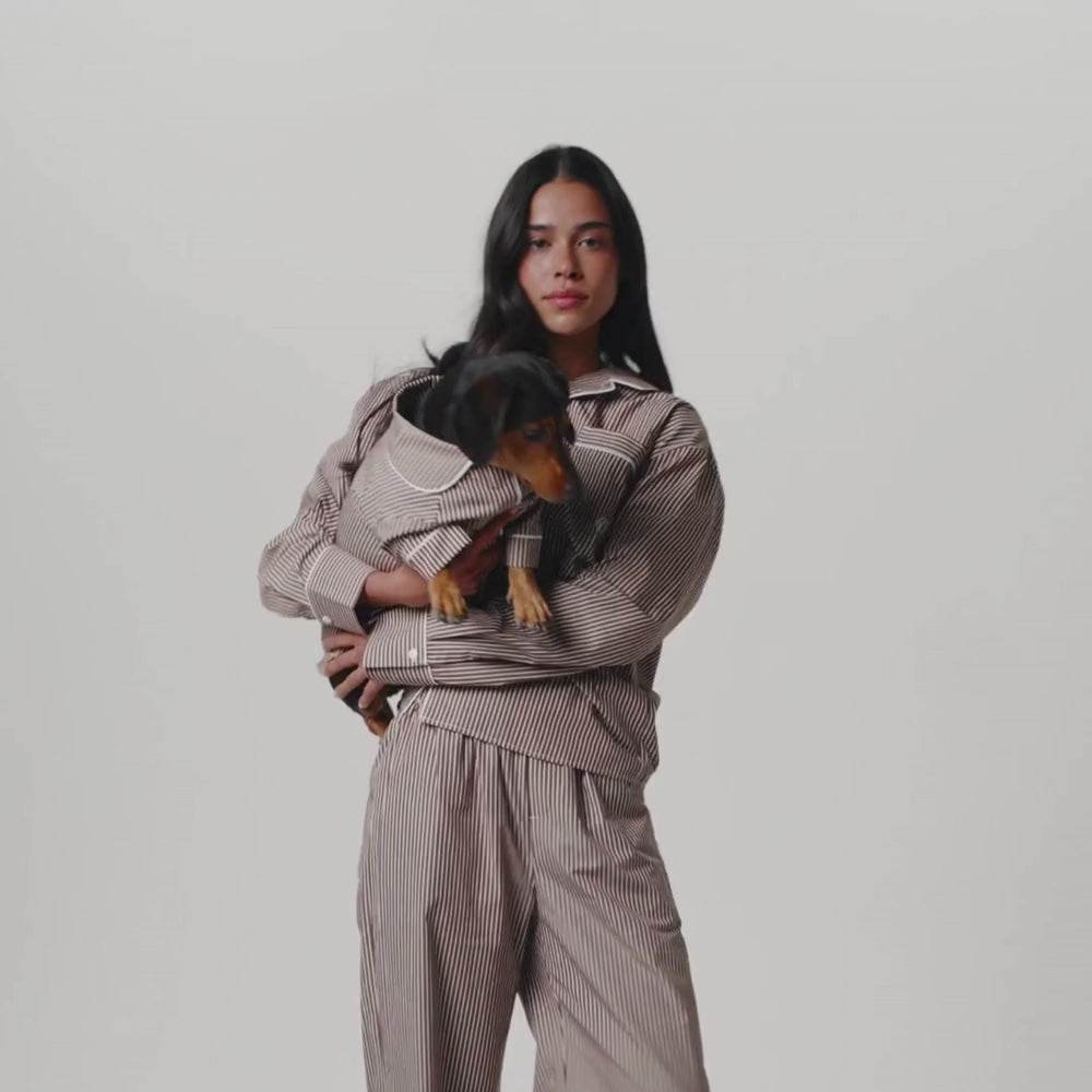 girl and dog in matching brown and white striped PJs